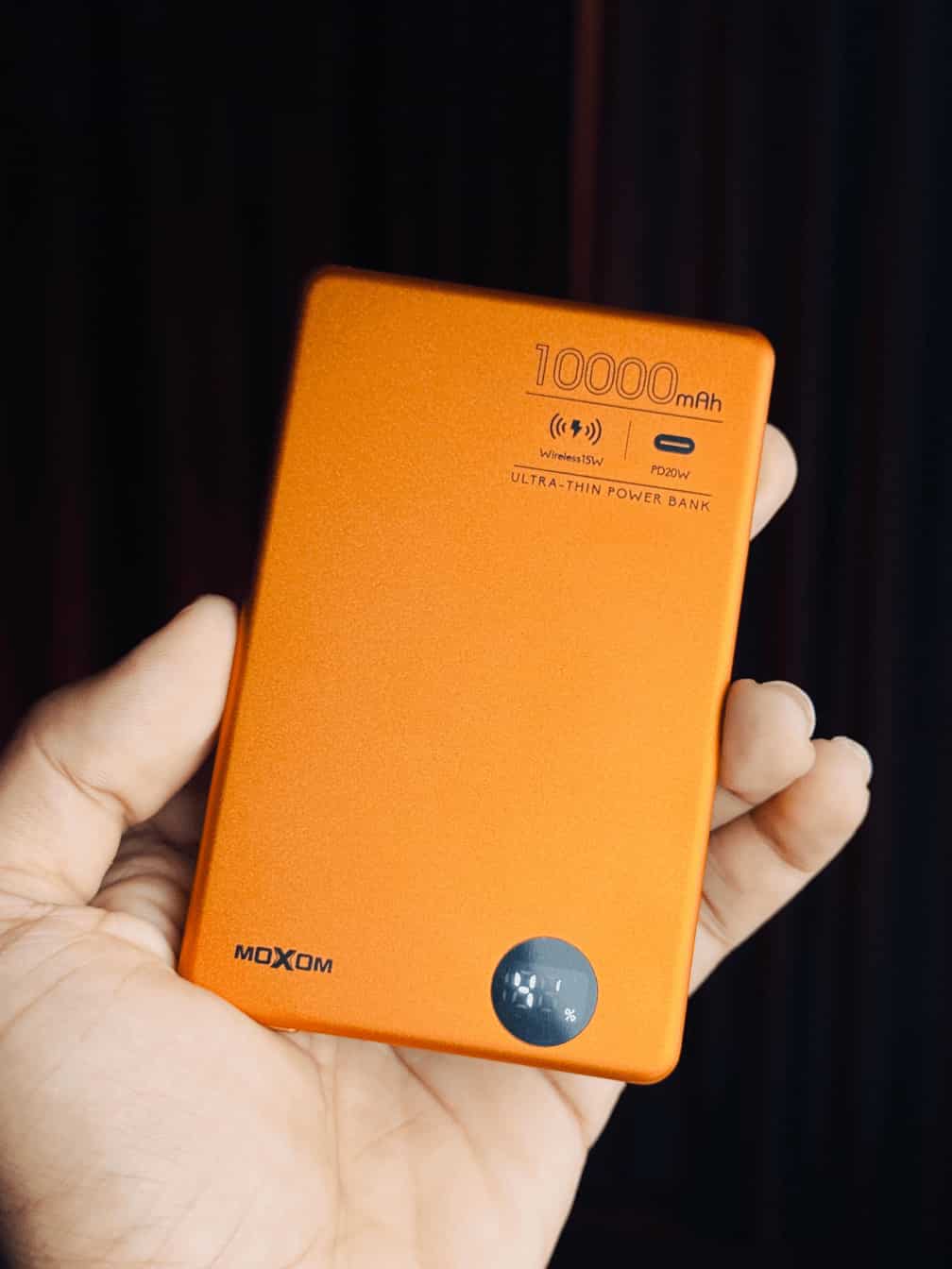 "MOXOM 10,000mAh wireless power bank with a matte finish, magnetic charging surface, and an LED display showing battery levels."